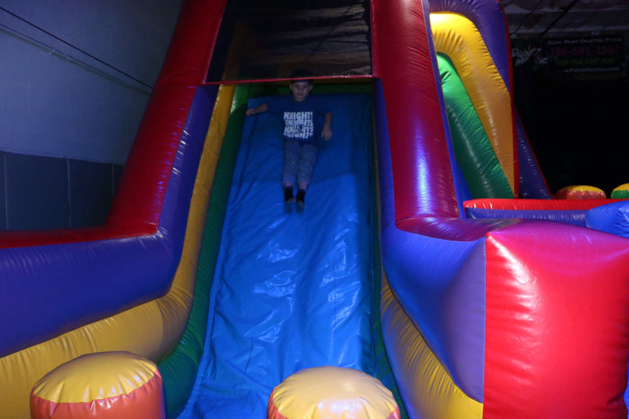 Child descending the inflatable slide at All Star Party World