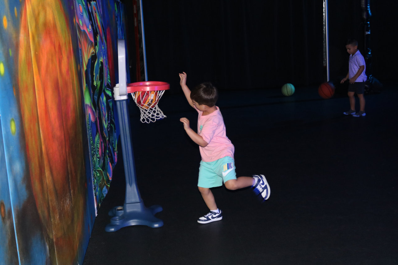 Child making a mini basketball layup at All Star Party World