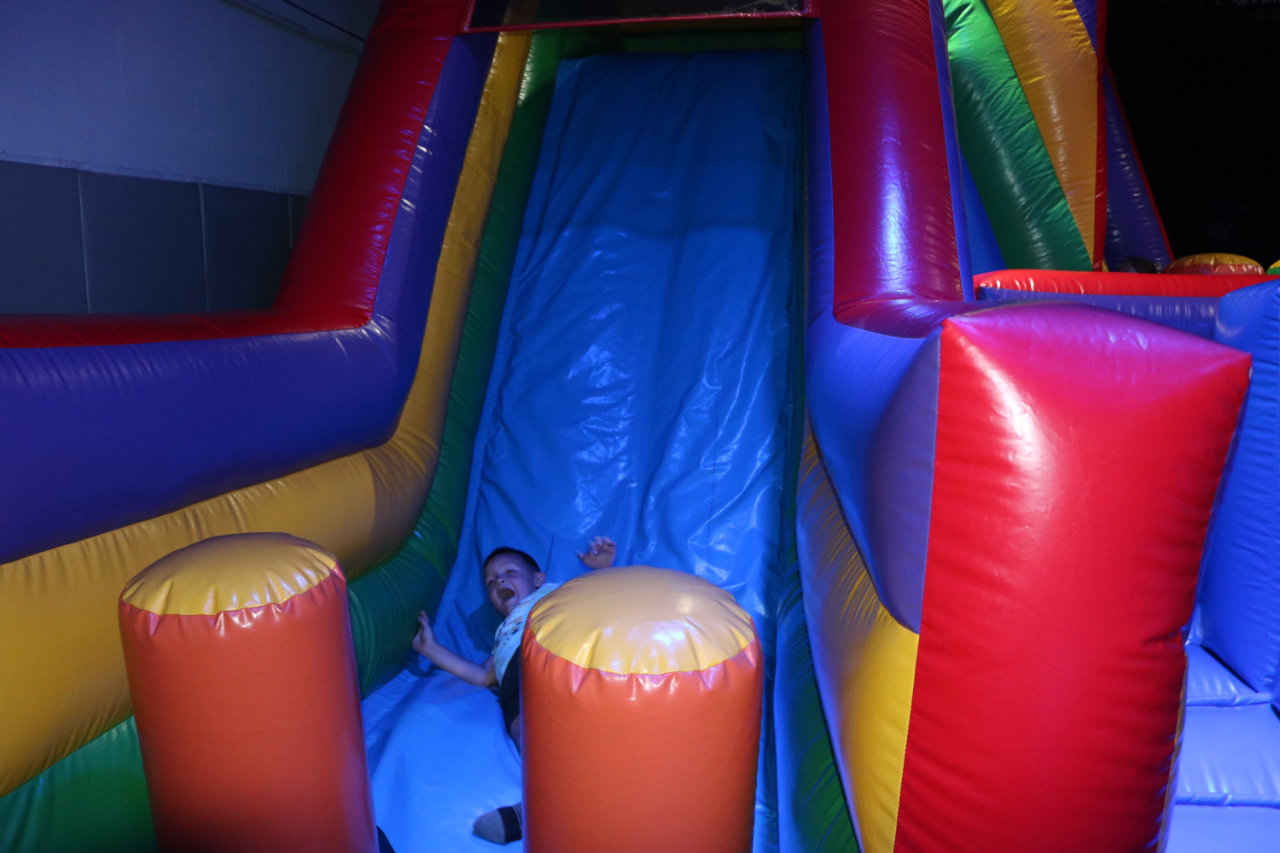 Child seated at the bottom of the inflatable slide at All Star Party World