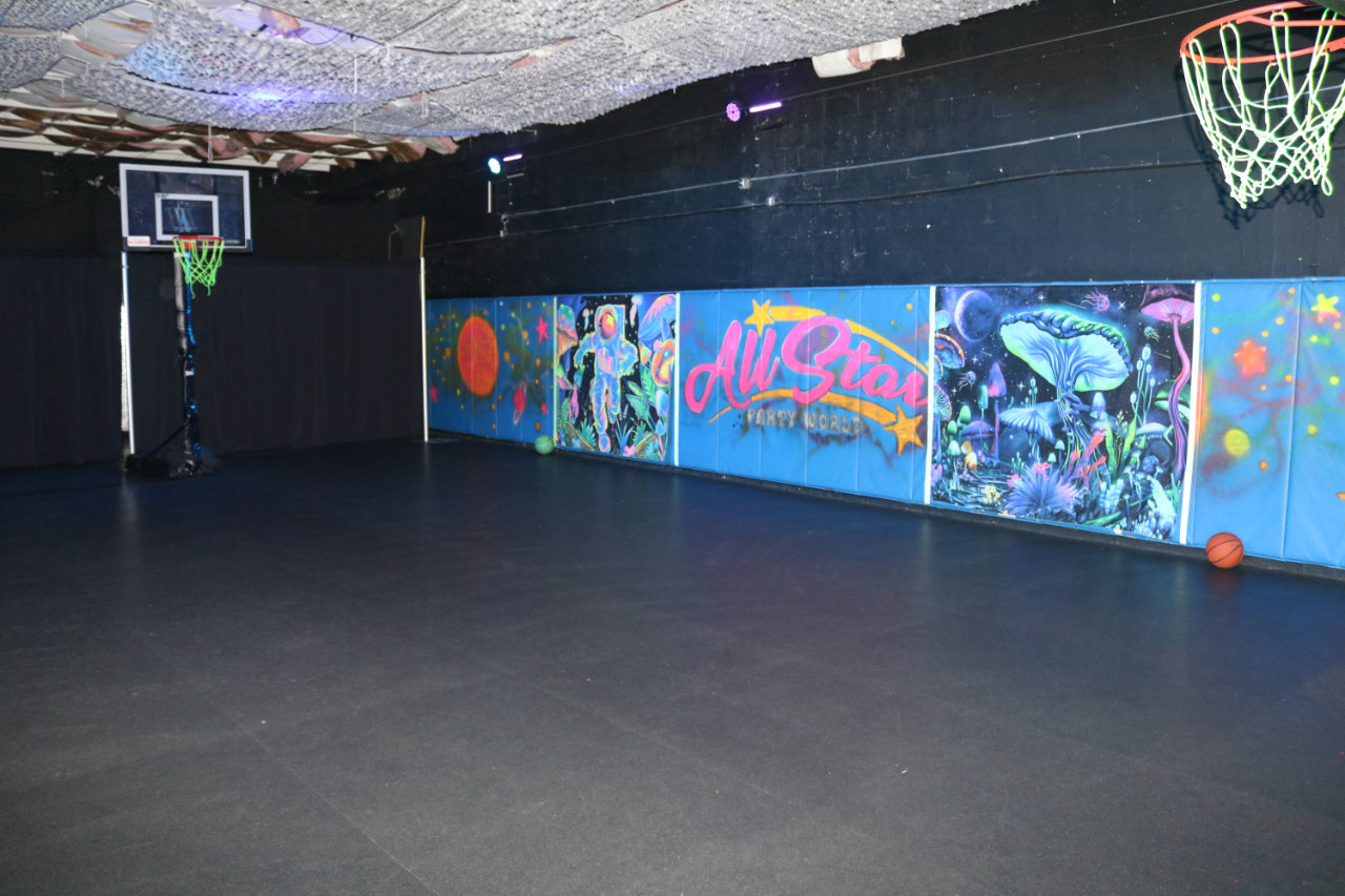 Indoor basketball court with colorful mural at All Star Party World