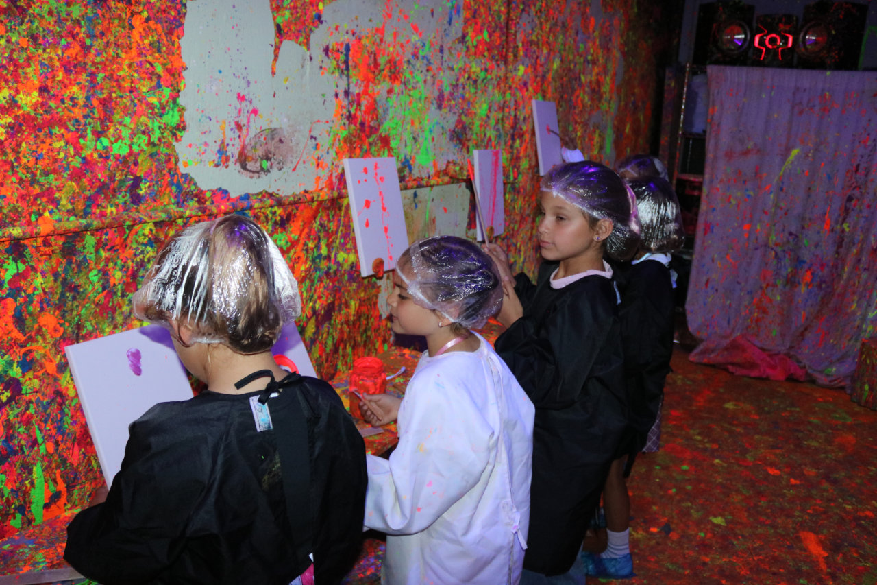 Close-up of kids painting canvases at All Star Party World