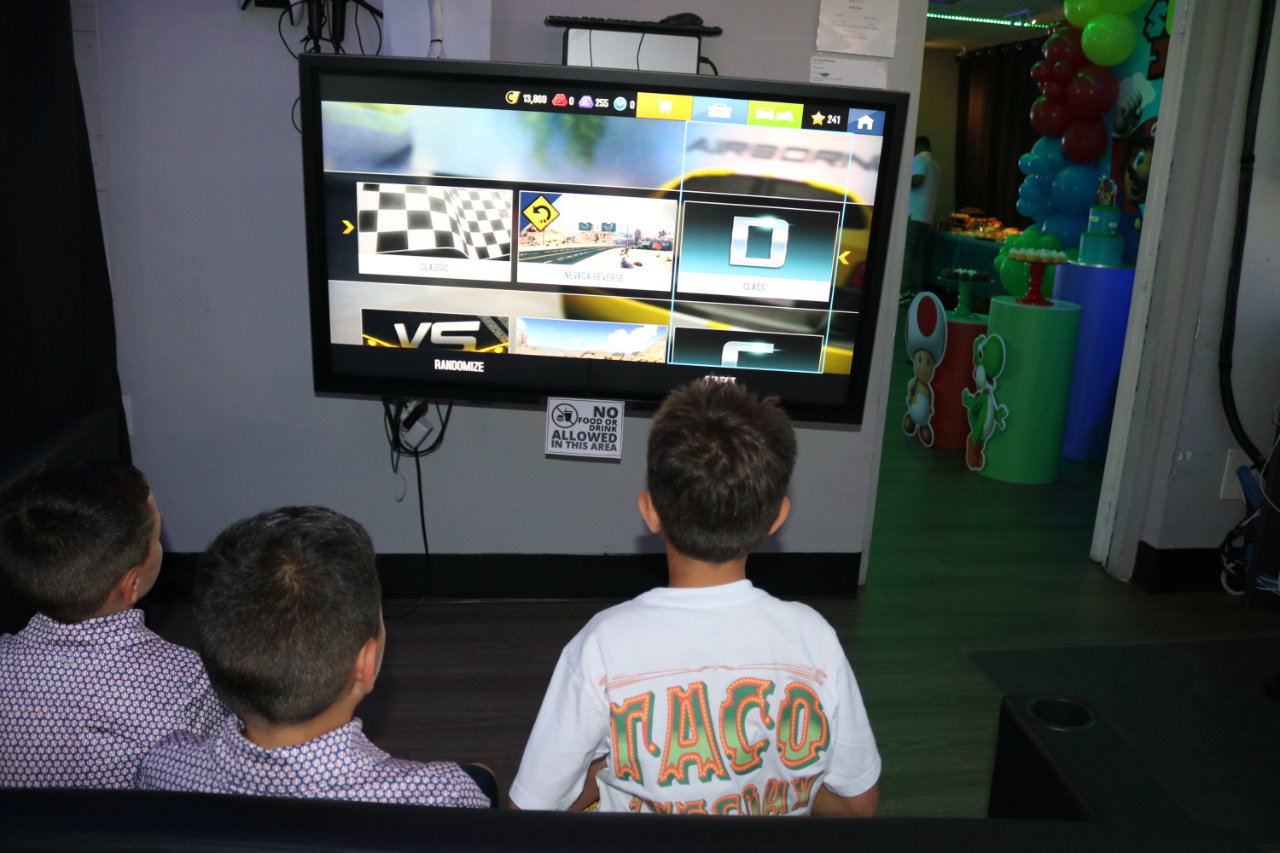 Kids playing racing video game at All Star Party World