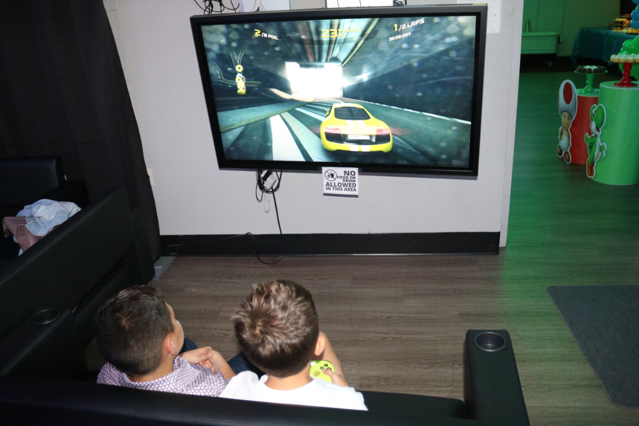 Kids playing racing video game at All Star Party World