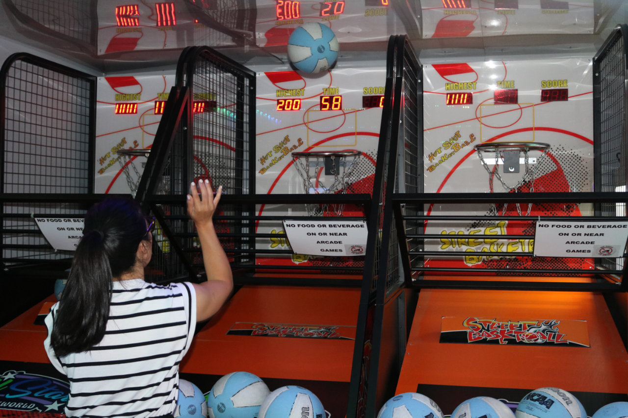 Woman playing arcade basketball at All Star Party World
