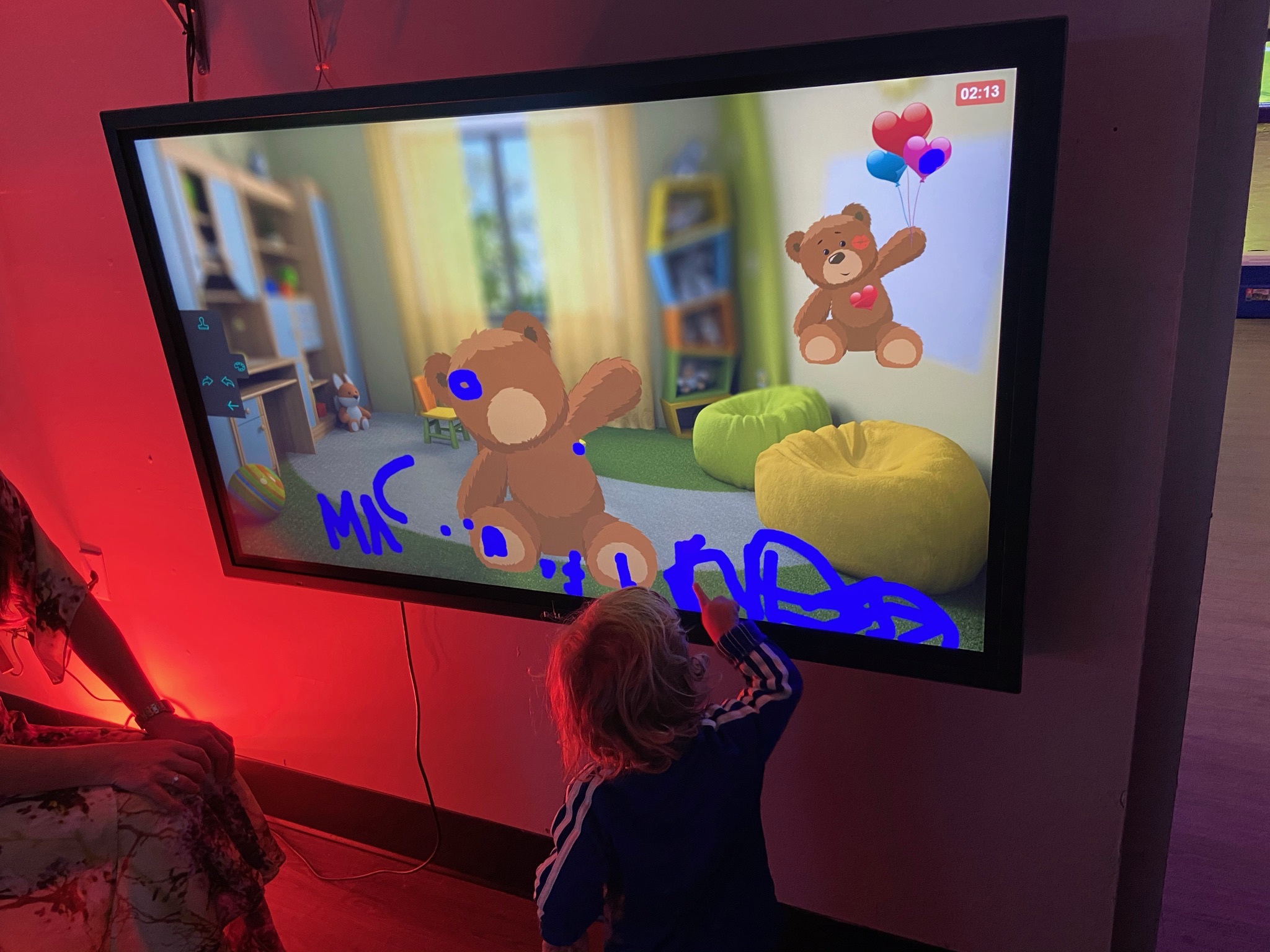 Toddler playing with an interactive touchscreen bear game at All Star Party World